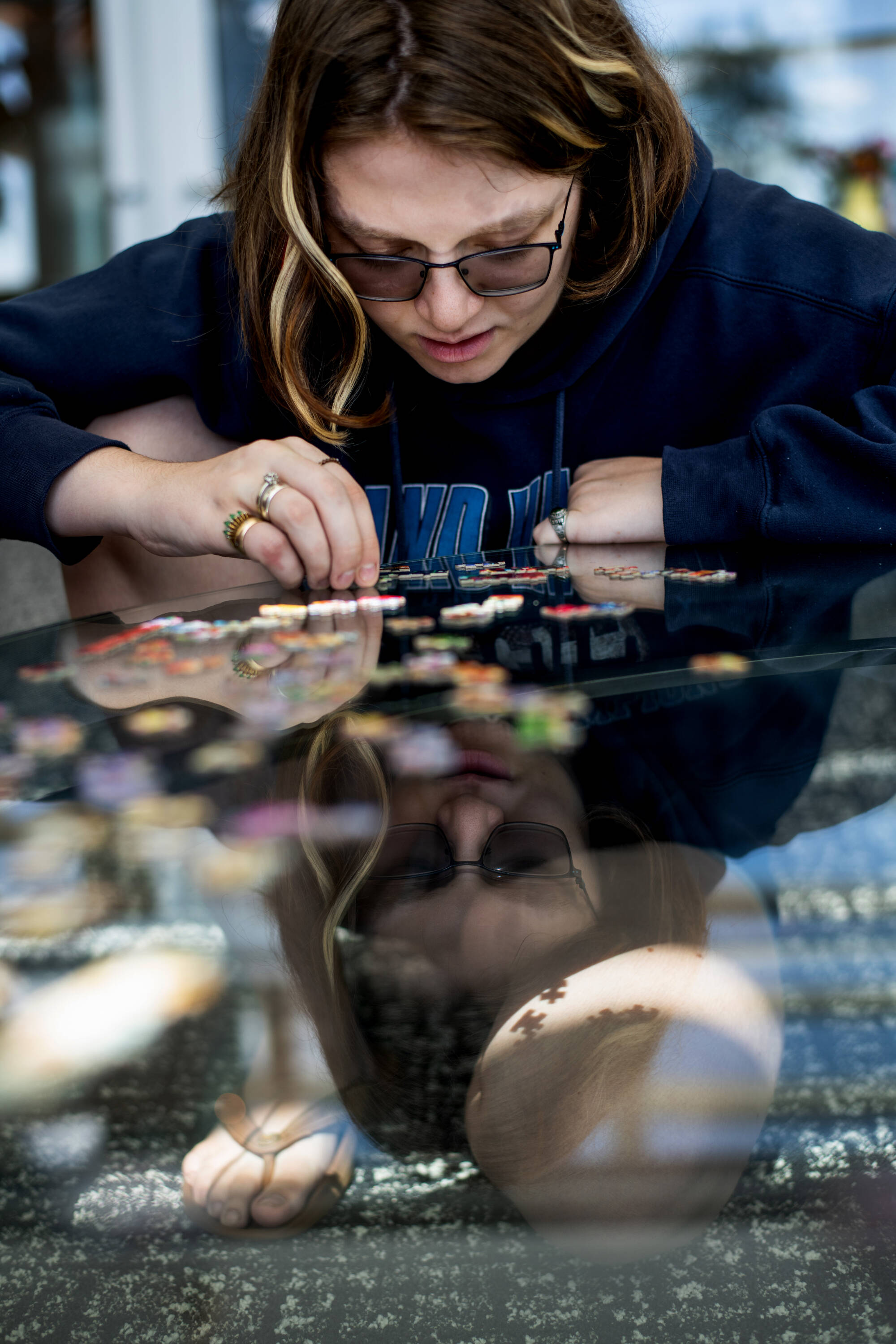 student leaning over table top, doing a puzzle